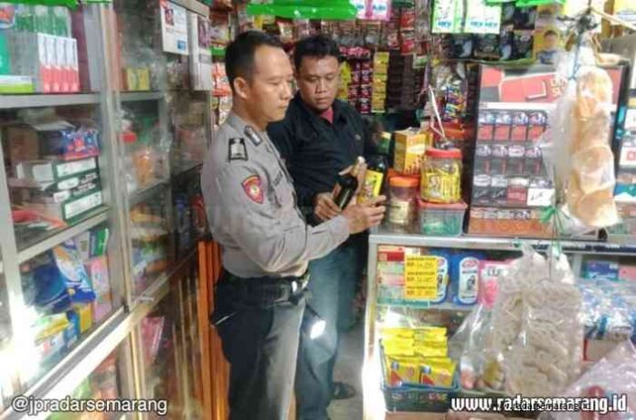 RAZIA: Kapolsek Wiradesa AKP Yorisa Prabowo menunjukkan puluhan botol miras yang disita dari delapan warung dan kafe. (ISTIMEWA)
